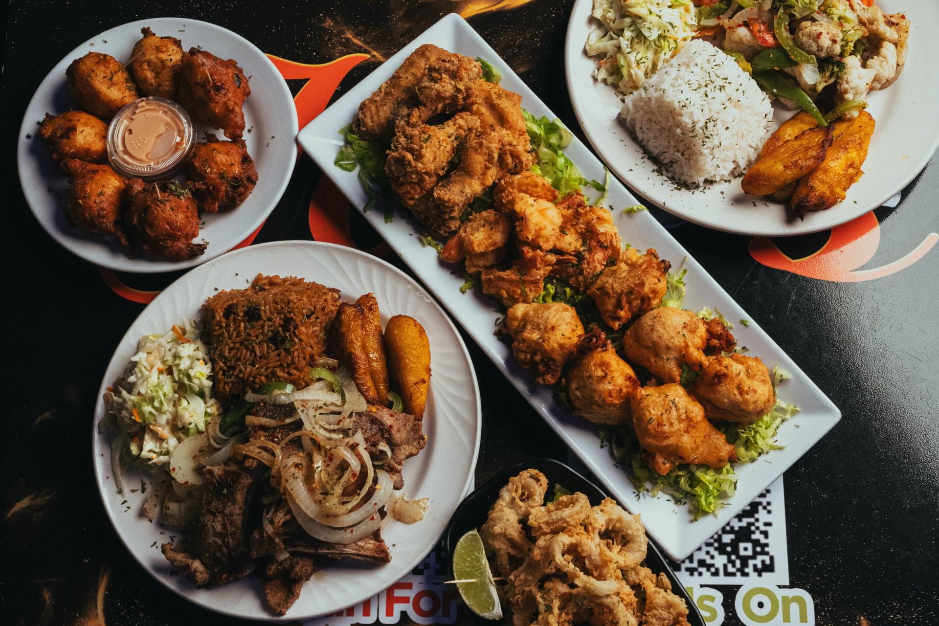 A table of Joey's dishes including conch fritters, cracked conch, calamari, wings, pork chops and seafood